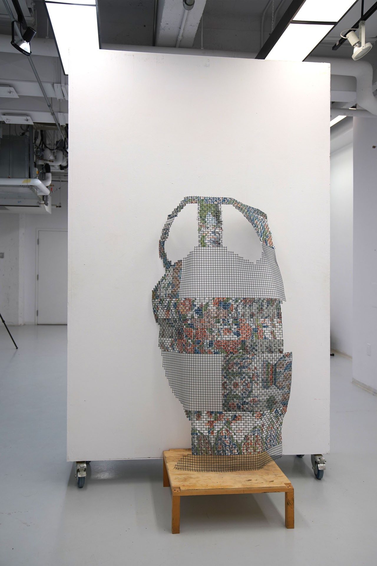 A sculptural object resembling a deconstructed woven vase displayed against a white wall