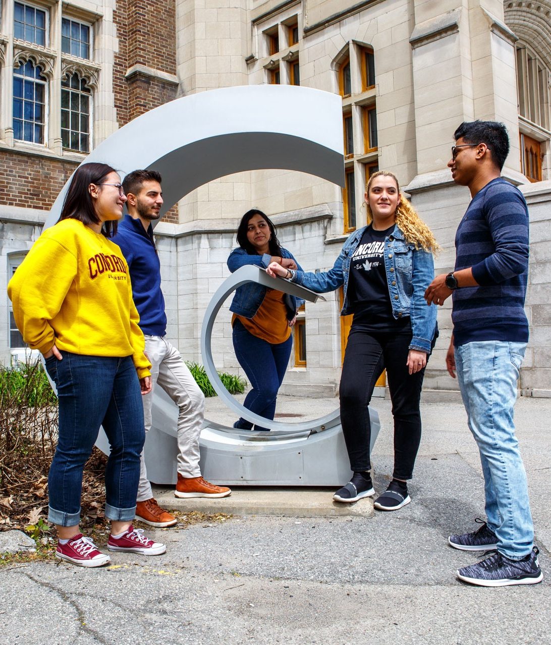 A group of students in conversation by a statue on Concordia University's Loyola Campus A group of students in conversation by a statue on Concordia University's Loyola Campus