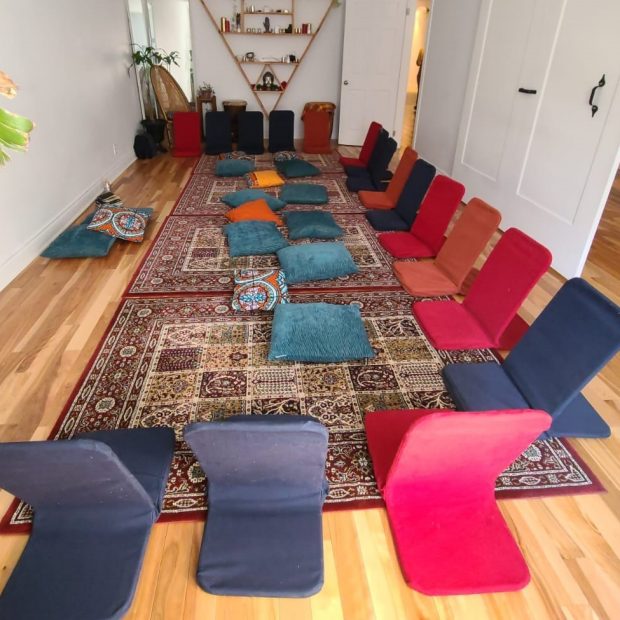 A photograph of a room set up with floor-chairs in a circle on a carpet.