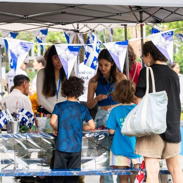 A photograph of children being shown art supplies at an outdoor event.