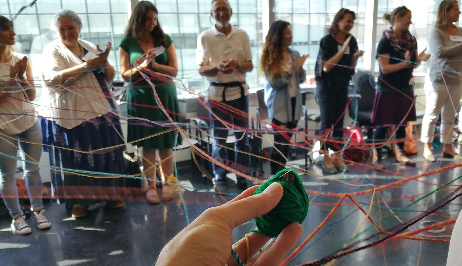 image features a group of people interconnected through an activity with playdoh and yarn