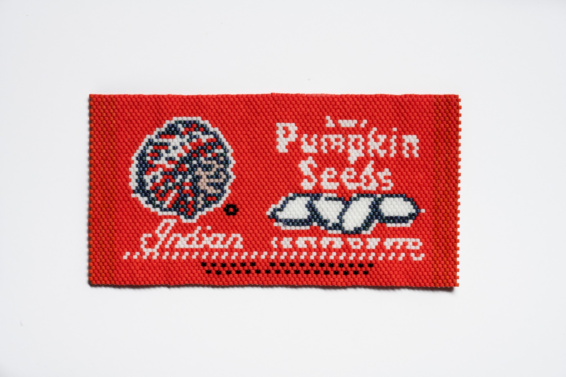 A beaded reproduction of a red wrapper of "Indian Pumpkin Seeds"