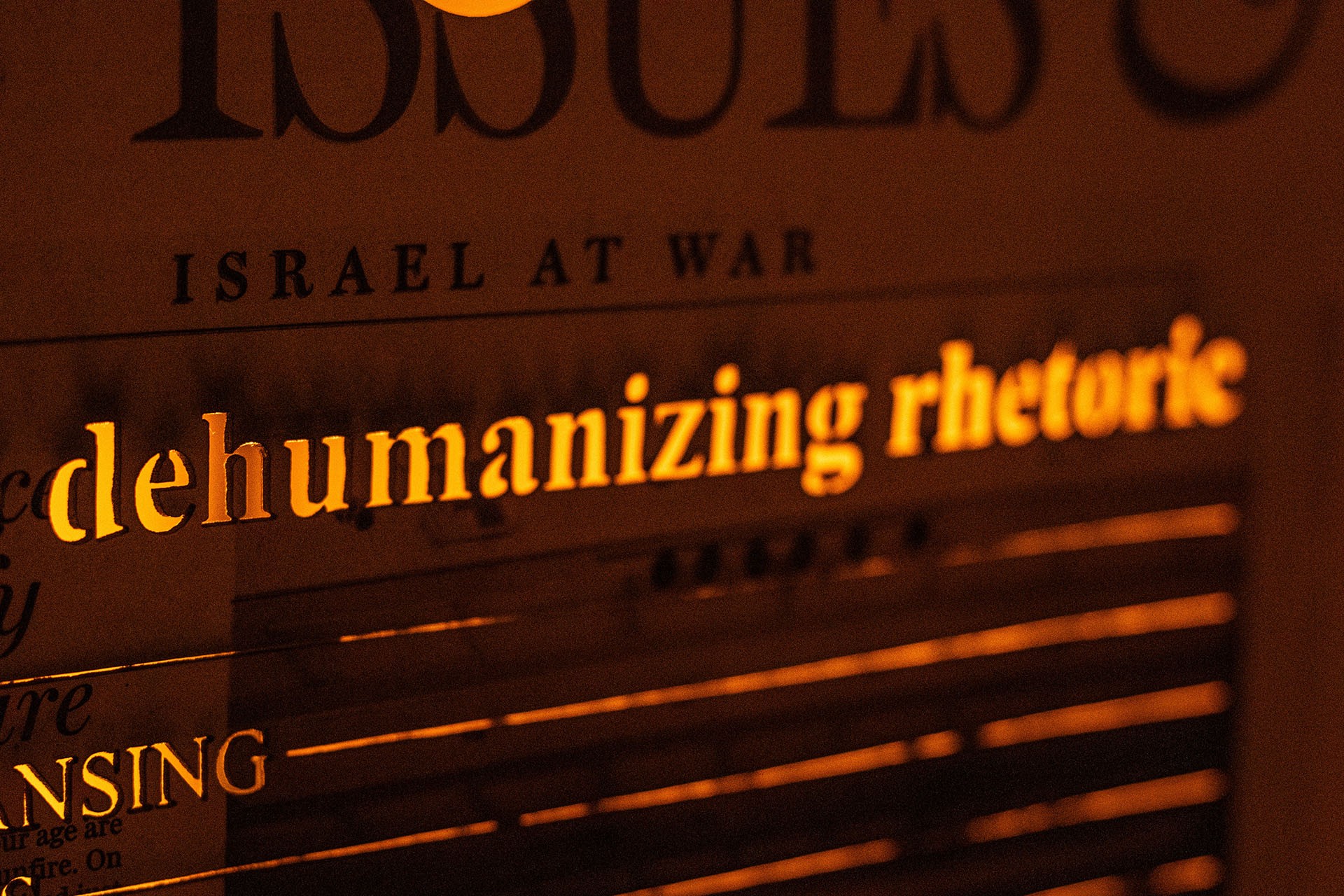 Detailed image of the work featuring a fraction of the title of an article stating “Israel at War”, and below it in cut-out letters, “dehumanizing rhetoric”.