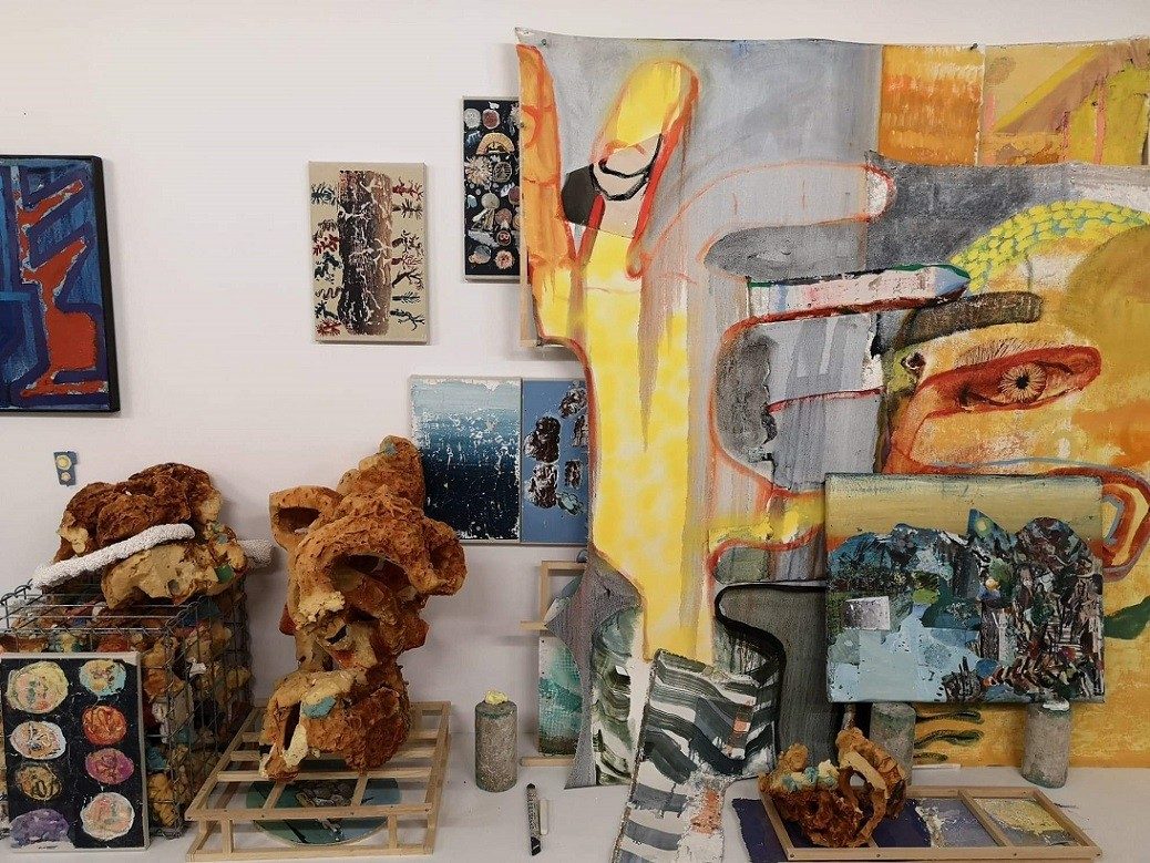 vue d'ensemble de l'atelier partagé par James Gardiner et David Lafrance, des sculptures et des peintures colorées et abstraites sont exposées, elles se chevauchant sur les murs et le sol.