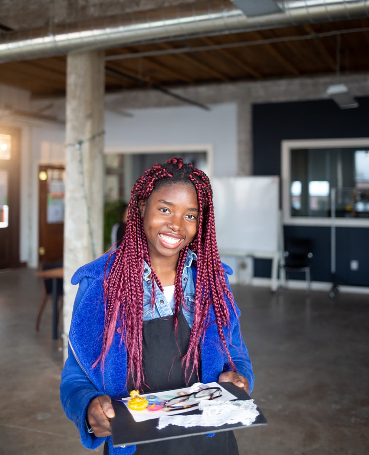 Creative Arts Therapies Female BIPOC student holding art supplies and smiling at the camera