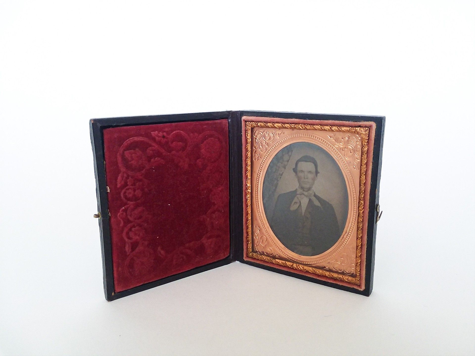 Ambrotype of a man with an oval copper frame in a small case.