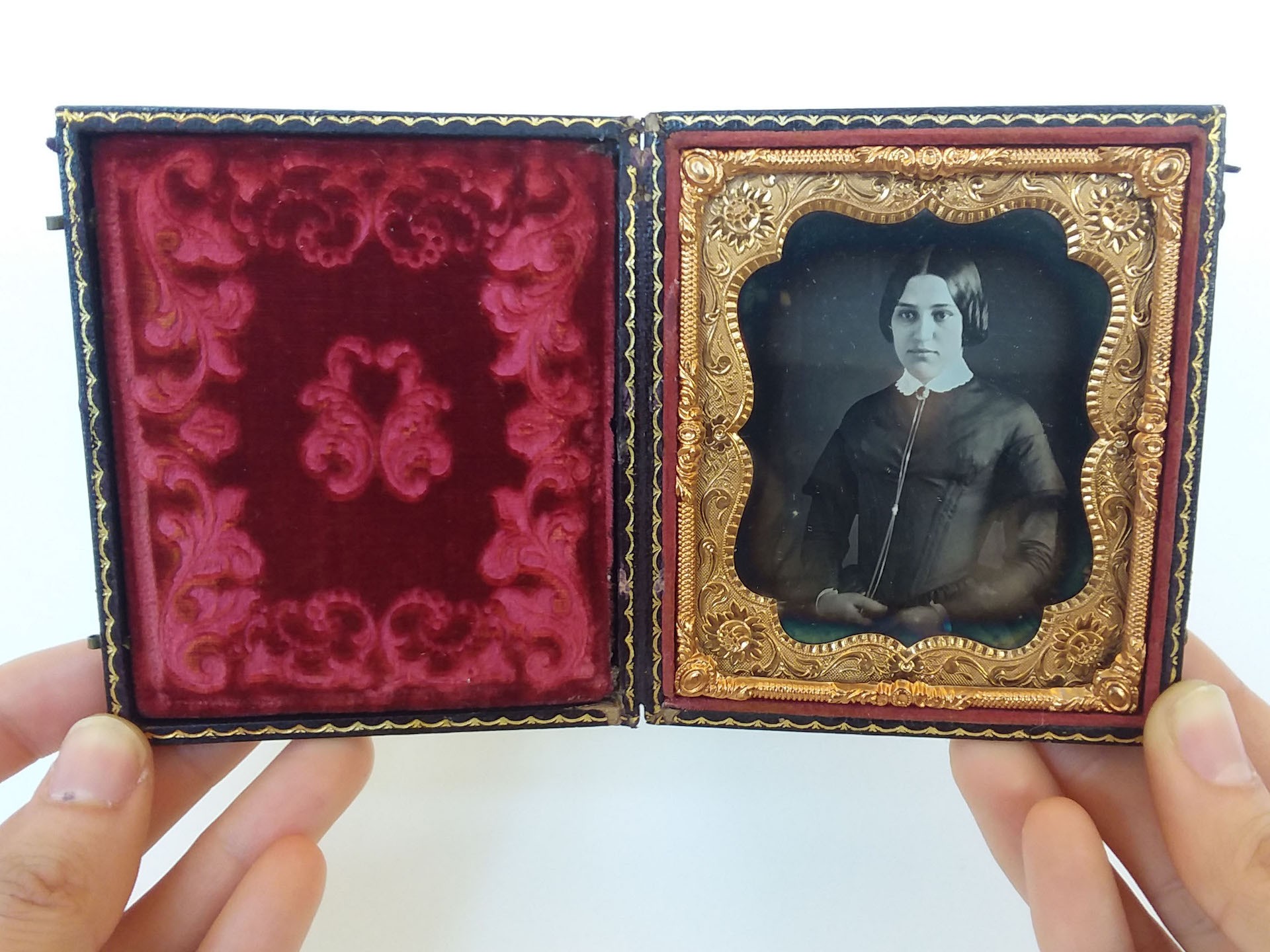 daguerreotype of a woman with an ornate gold frame in a small case