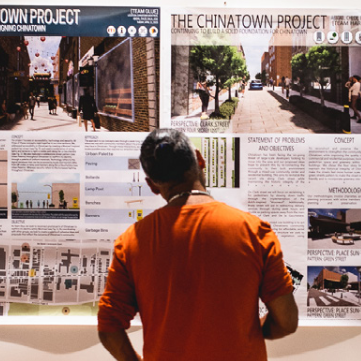 Photographie d'une personne debout devant des affiches sur l'histoire de Chinatown.