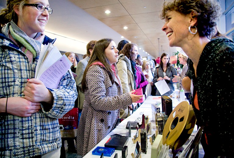 students interacting with staff behind tables