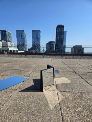 Mirrors on a rooftop reflecting the sun against a background of skyscrapers and a blue sky