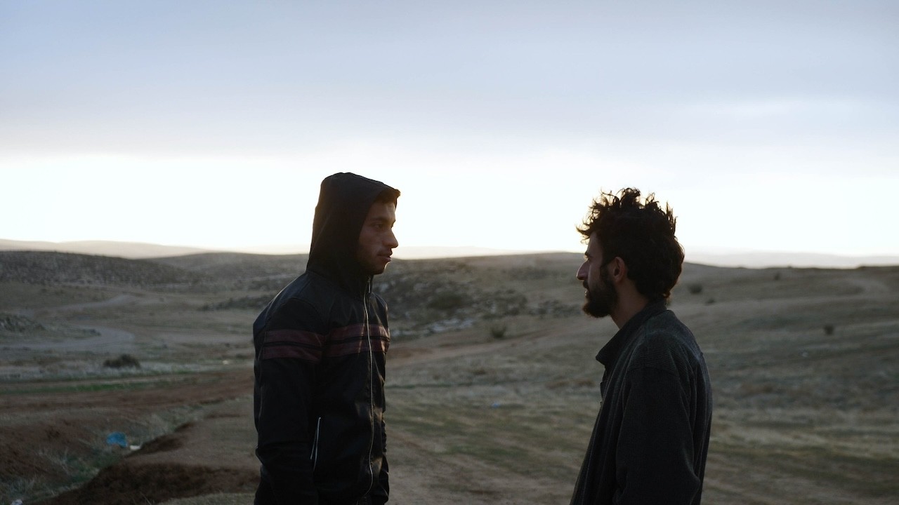 Two men in a desert landscape staring at each other