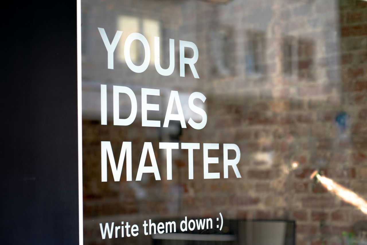 The words Your Ideas Matter (write them down) are painted onto a window