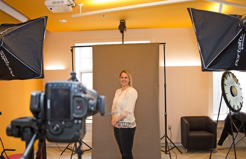 A woman poses for a camera in front of a coloured backdrop