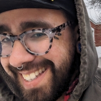 man wearing glasses and beard smiles at camera