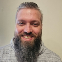 man with beard smiles at camera