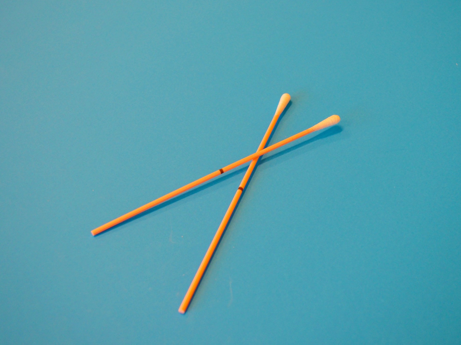 Two orange medical swabs on a blue background