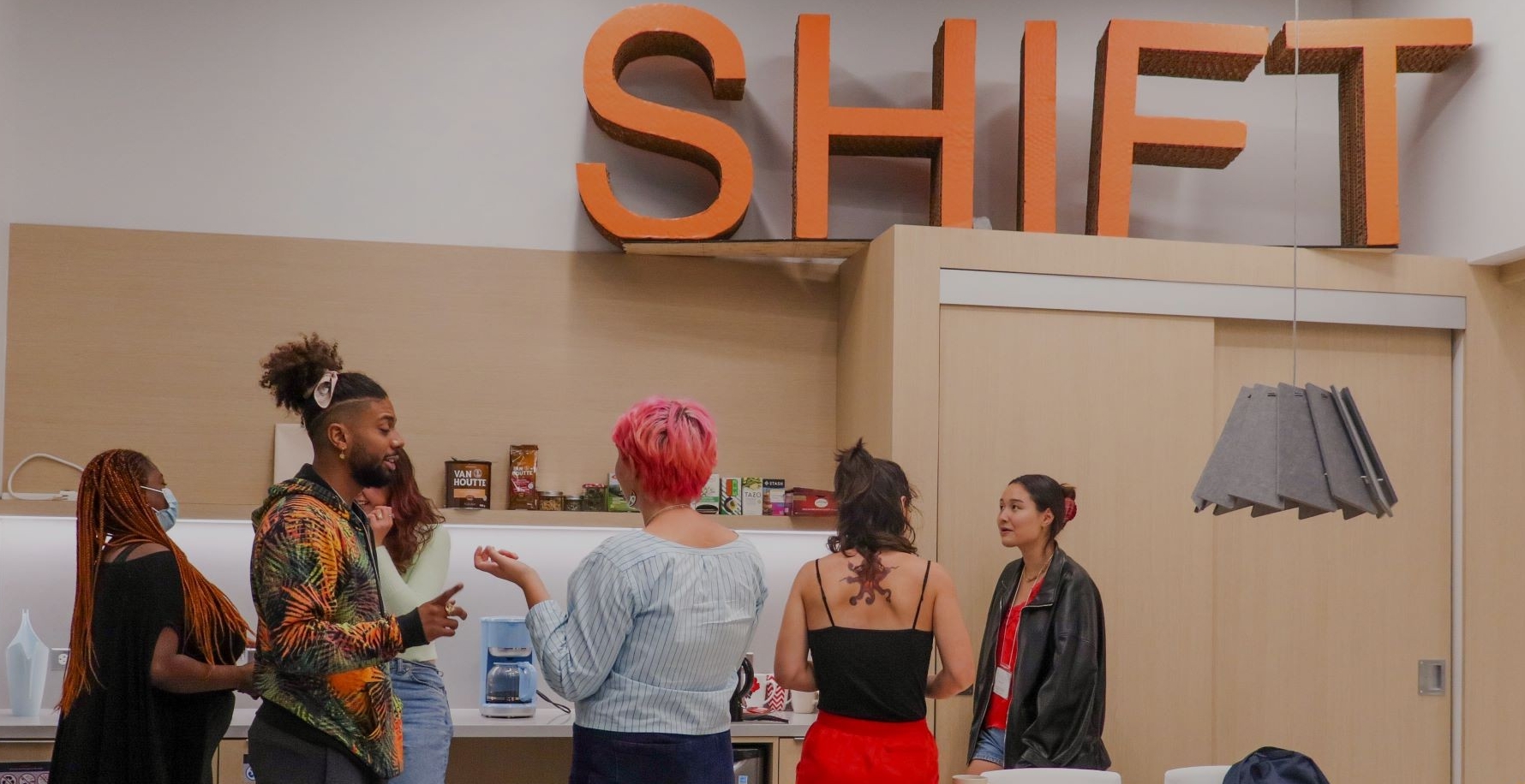 6 student interns chatting in front of the SHIFT Centre's coffee area.