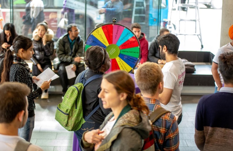 A group of people standing around a wheel.