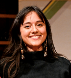 A smiling young woman with dark hair wearing a black turtleneck.