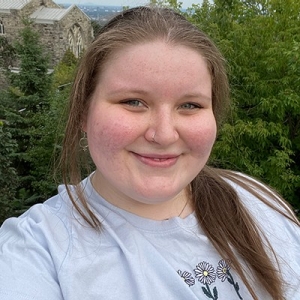 Smiling young woman with long, dark blonde hair, wearing a grey t-shirt