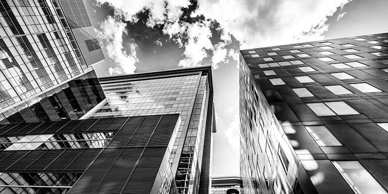 A black and white photo of city buildings seen from below