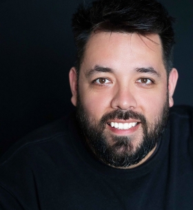 a smiling man with a beard looks at the camera