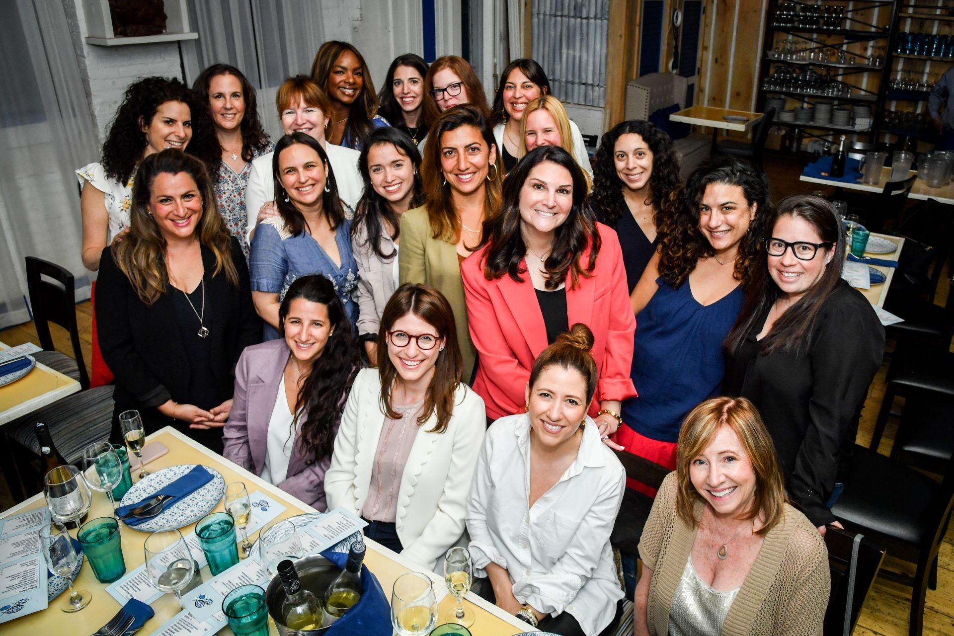 A group of women gather around drinks at a restaurant.