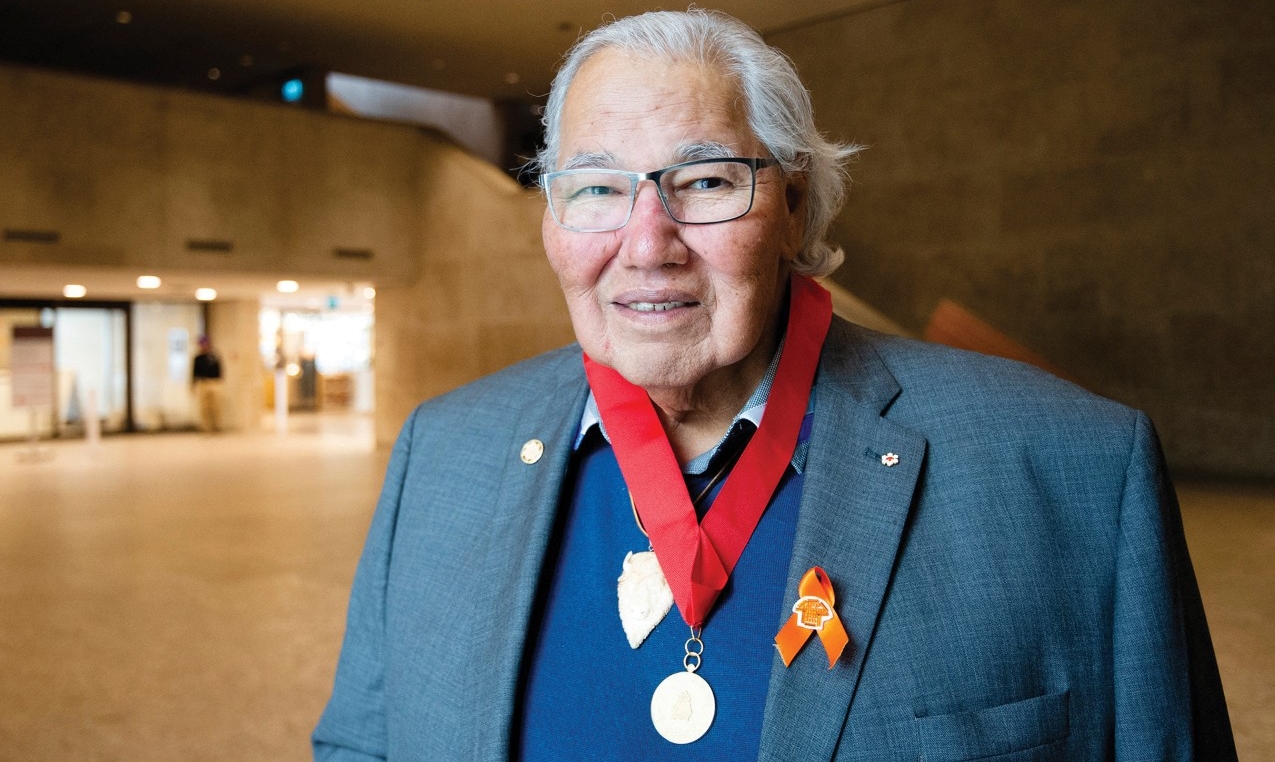 Man wearing a suit jacket, with a golden medal hanging from a red ribbon