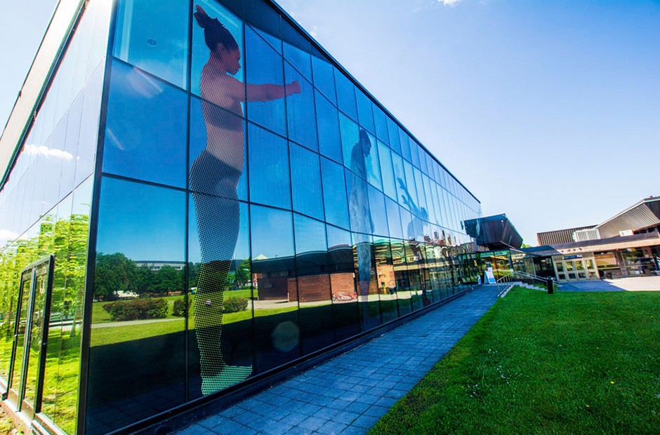 Against a blue sky, a modern building with a graphic of an athlete about to leap