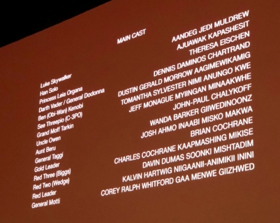 A list of film credits showing on a brown screen, including the name of 