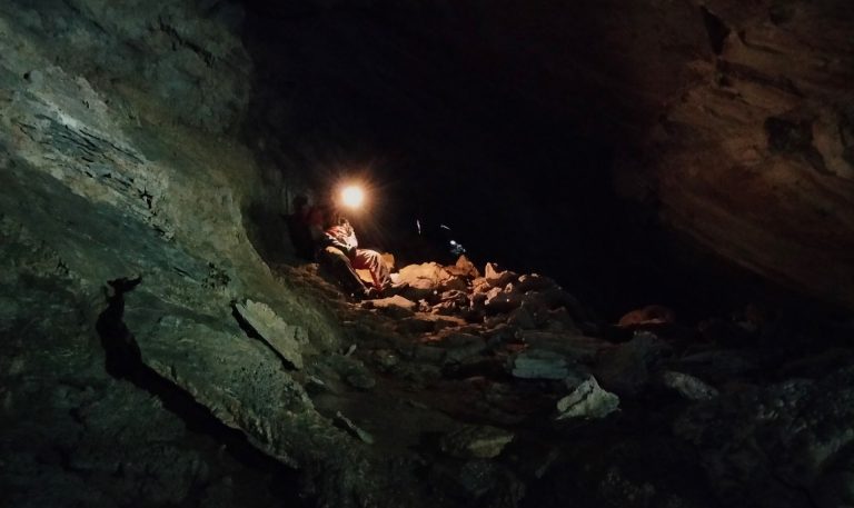 A head lamp illuminates the inside of a cave