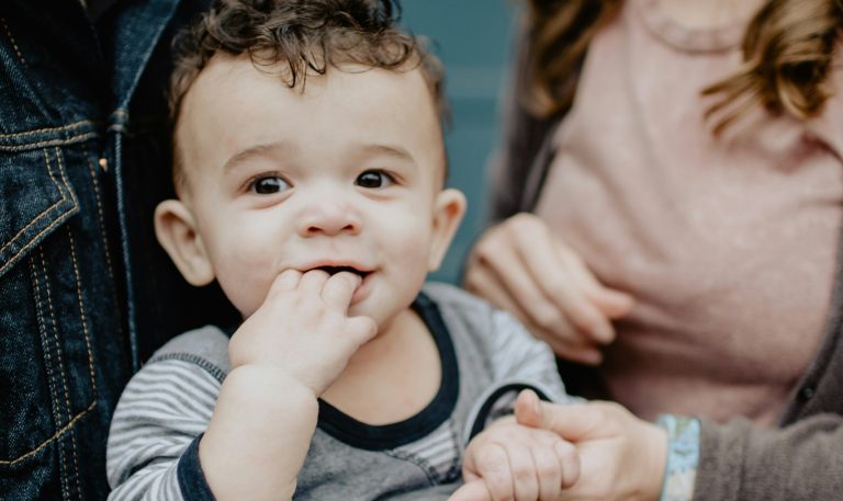 Un bambin aux cheveux bruns tenu par ses parents