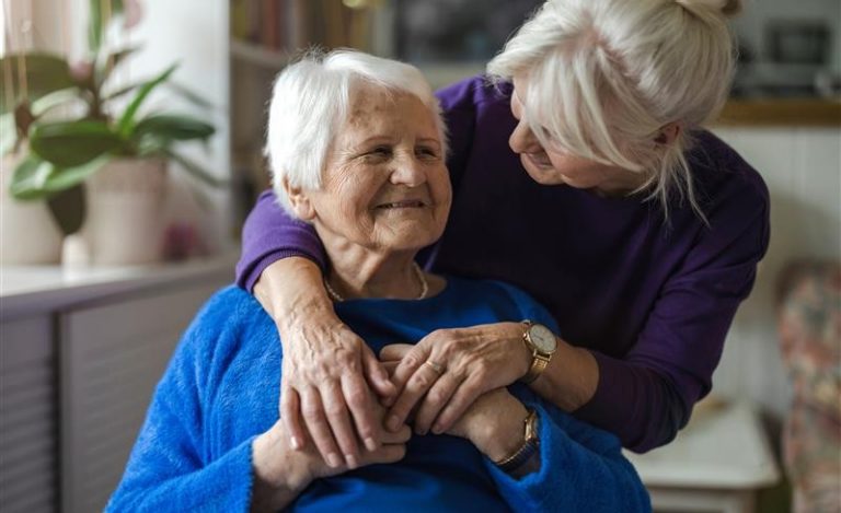 An older adult woman hugs her mother