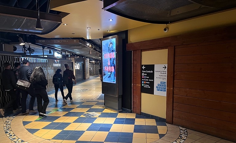 People in an underground tunnel area leading to public transport.