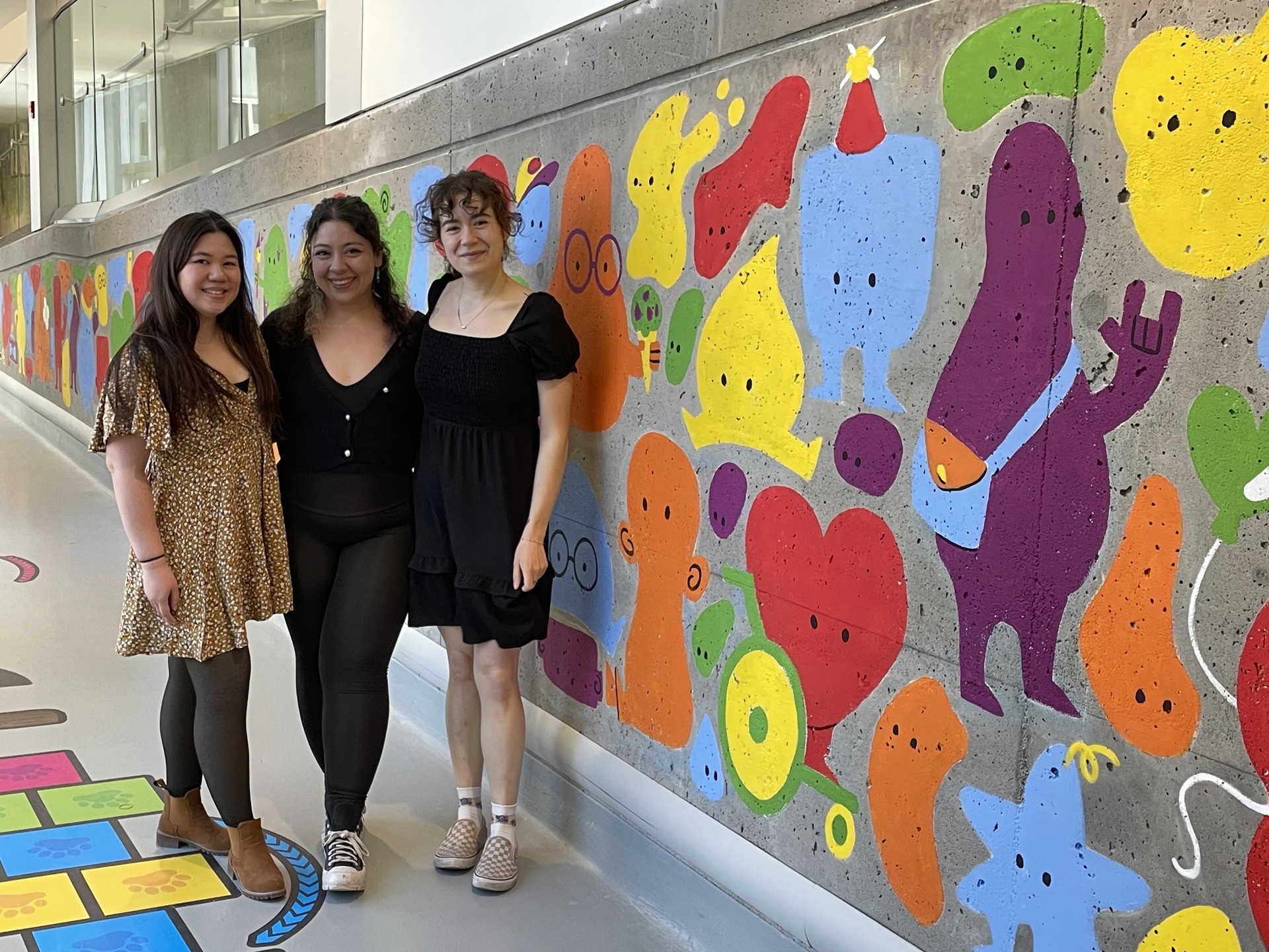 Trois jeunes femmes devant la murale au Centre Mackay