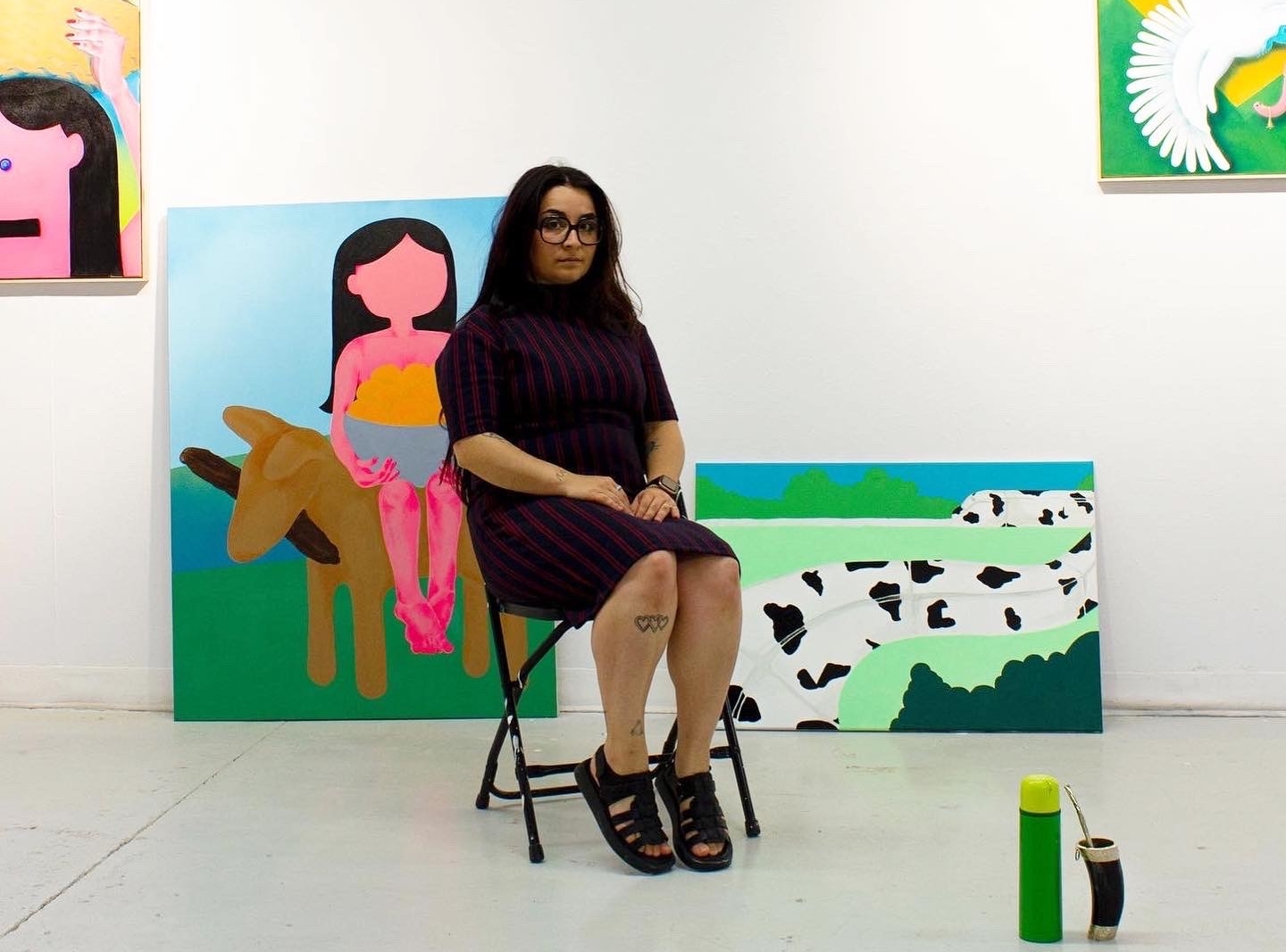 Femme assise dans une pièce avec des peintures colorées à l'arrière