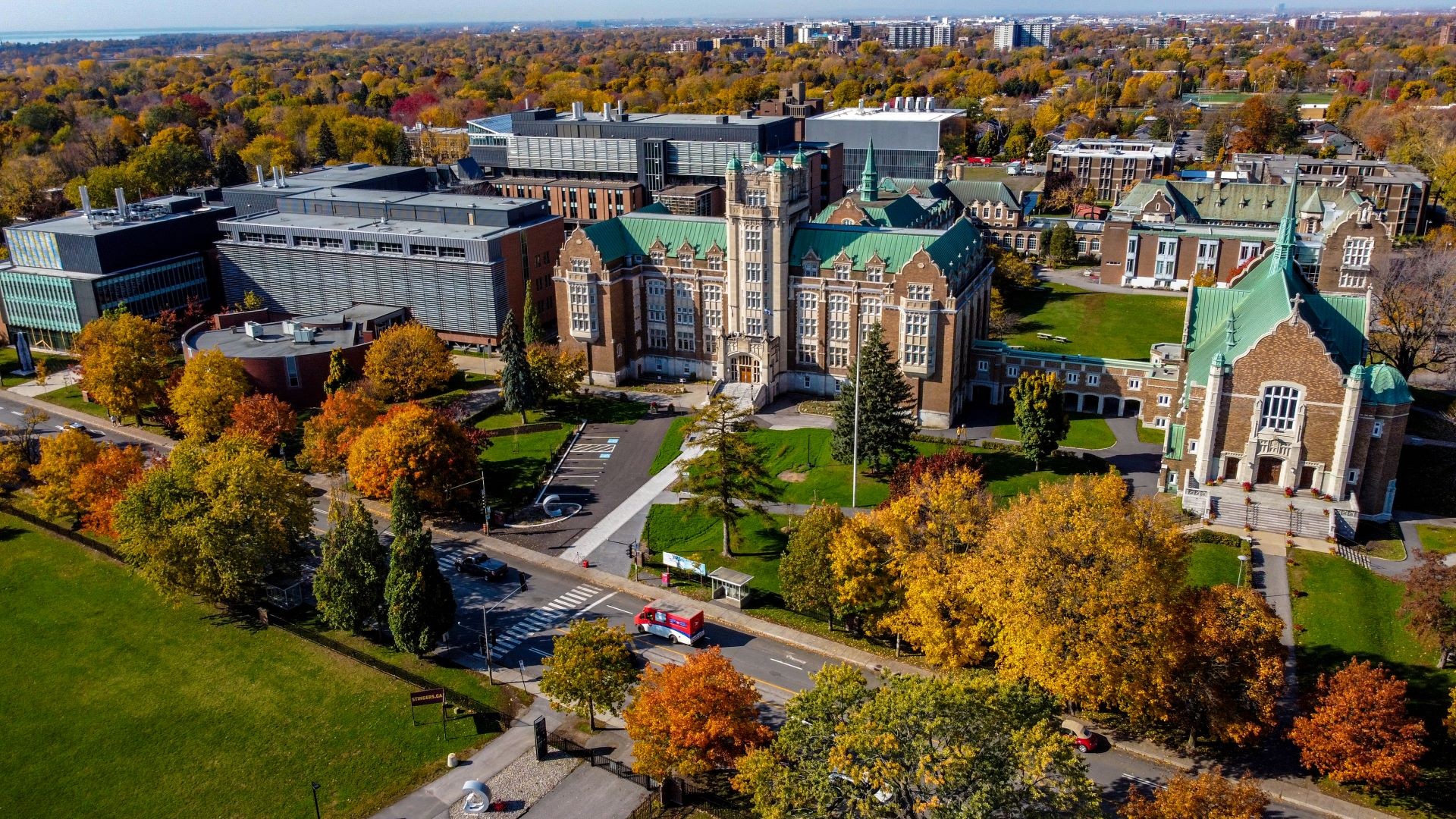 Vue aérienne d'un campus universitaire mêlant bâtiments modernes et historiques au milieu d'un feuillage d'automne.