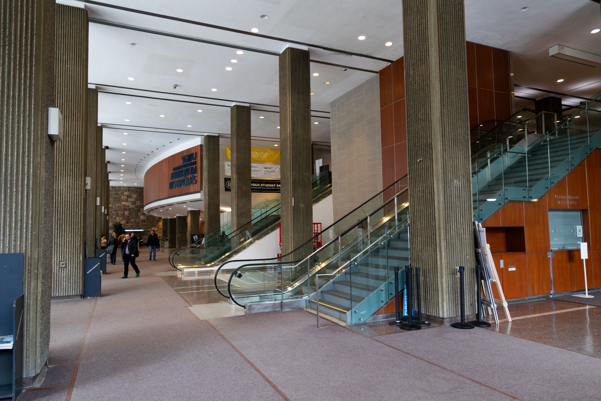Un hall d'université spacieux avec un mobilier moderne et des éléments architecturaux, y compris un escalier et de grandes fenêtres.