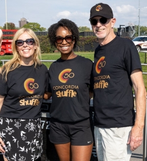 Trois personnes se tiennent côte à côte, toutes vêtues d'un t-shirt noir « Shuffle ».