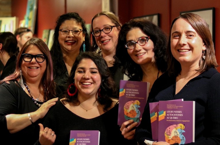 A group of smiling women wearing black, holding books